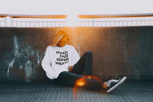 united states woman sitting and leaning on black wall woman